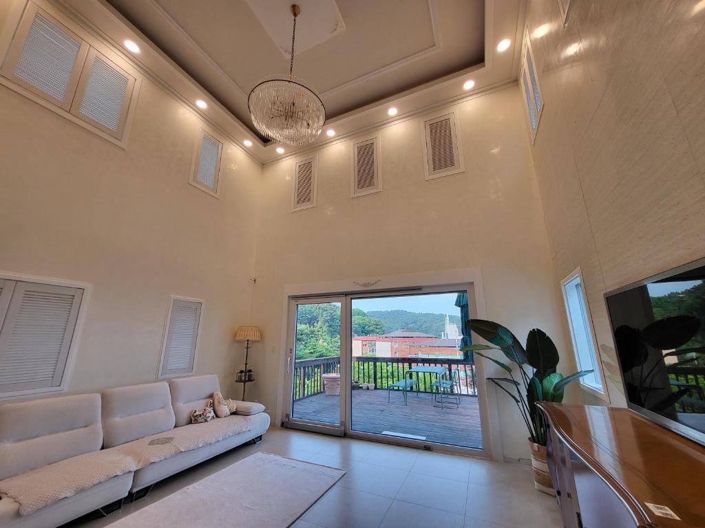 a living room with a couch and a sliding glass door at Haepung Stay in Yŏnamp'o