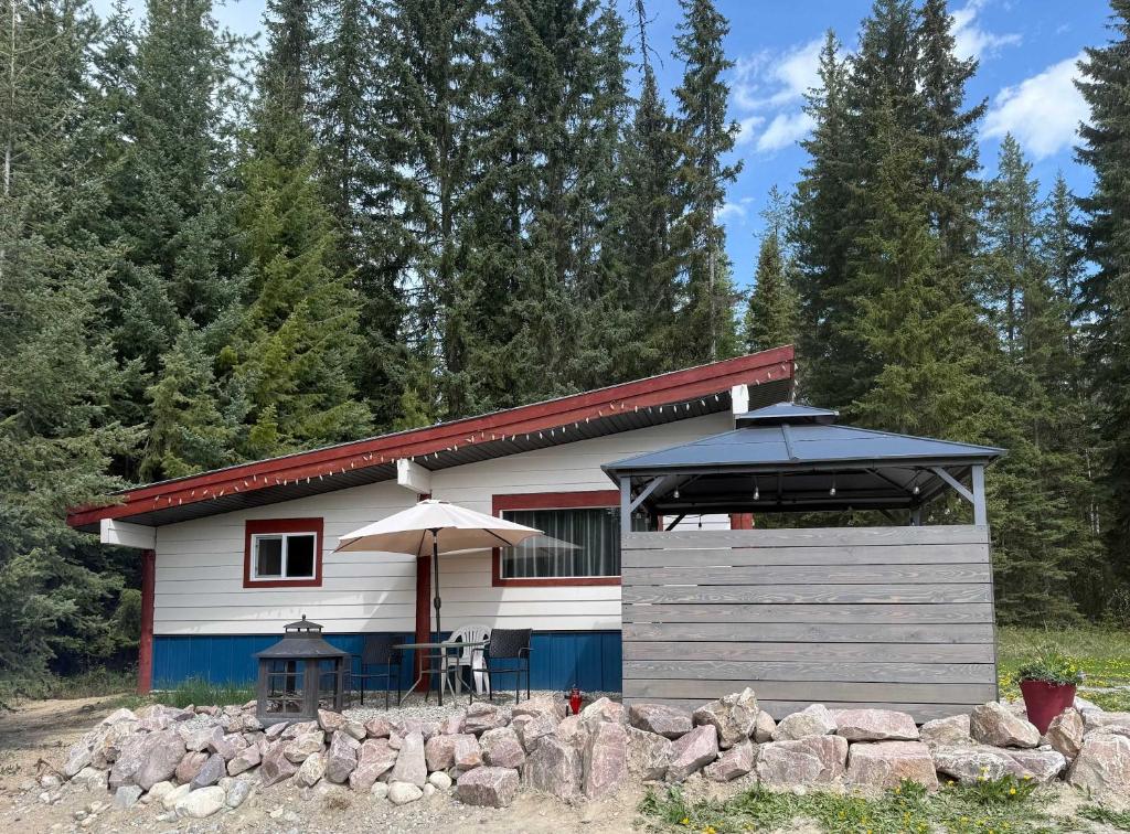 a small house with a table and an umbrella at Pine Marten Wilderness Cabin - Hot Tub & Mountain Views in Golden