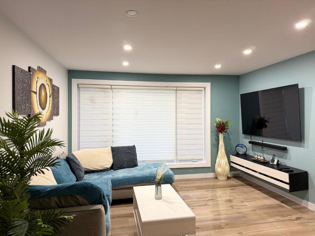 a living room with a blue couch and a flat screen tv at Manoir Chris in Saint-Augustin-de-Desmaures