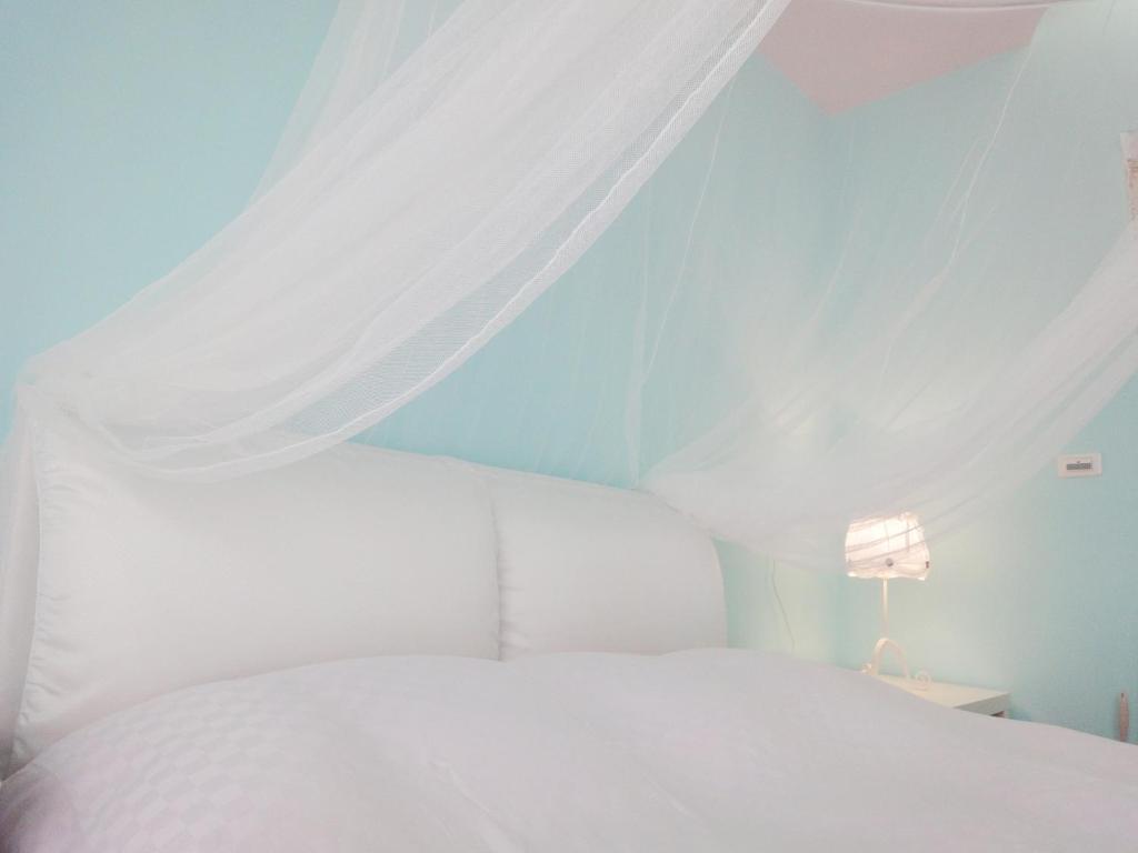 a bedroom with a white bed with a canopy at MINAMI Inn Kenting in Nanwan