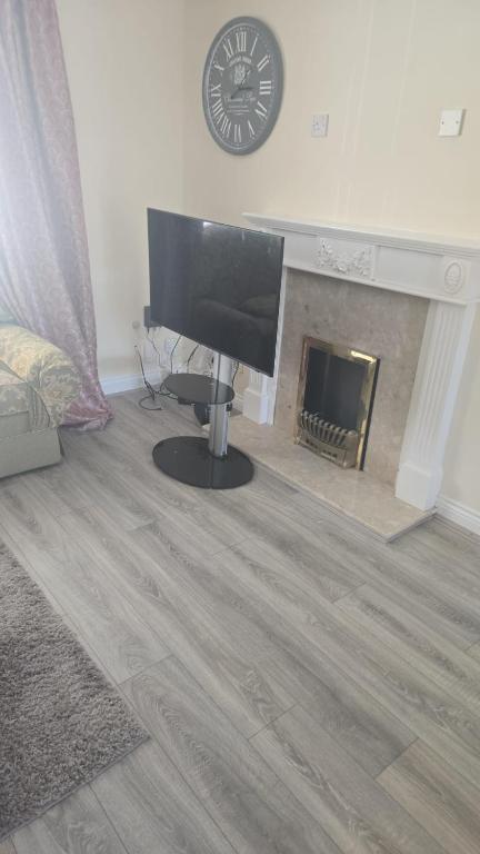 a living room with a television and a fireplace at Hilcot House in Kirby Muxloe