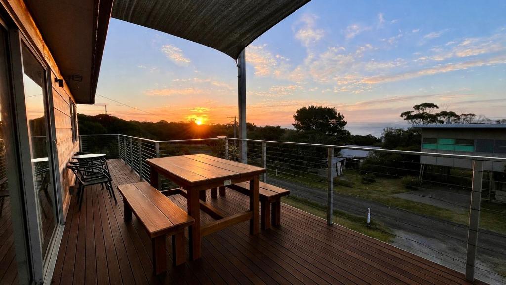 a wooden deck with a table and bench on a balcony at SeaSong in Ventnor in Ventnor