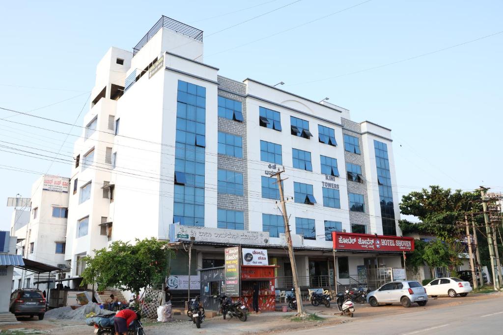 a large white building on the side of a street at Hotel Shoven in Dāvangere