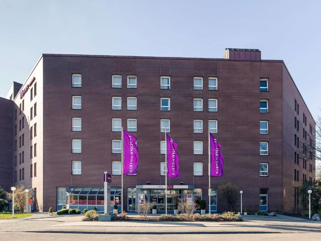 ein Gebäude mit lila Flaggen davor in der Unterkunft Mercure Hotel München Neuperlach Süd in München