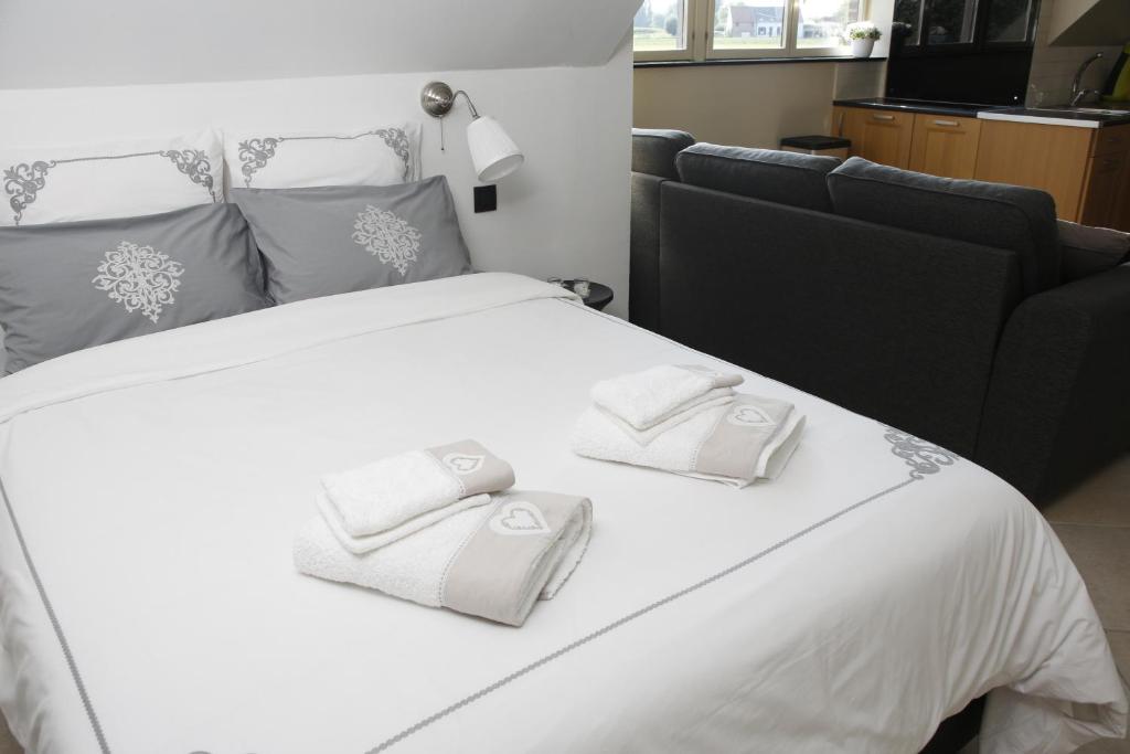 1 cama blanca grande con 2 toallas blancas. en Au Grenier des Coccinelles, en Pecq