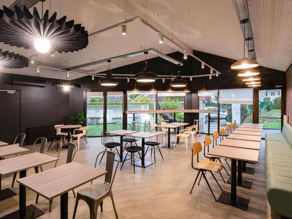 a restaurant with wooden tables and chairs and windows at ibis Cergy Pontoise Le Port in Cergy