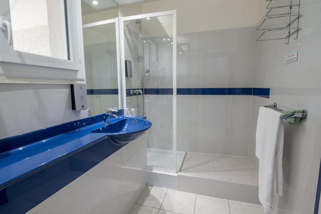 a bathroom with a blue sink and a shower at Citotel Hôtel Le Capricorne in Marmande