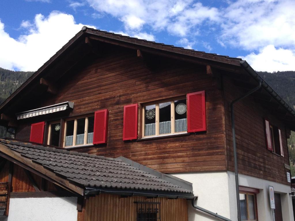 a house with red shutters and a clock in the window at Tgea sulagliva in Andeer
