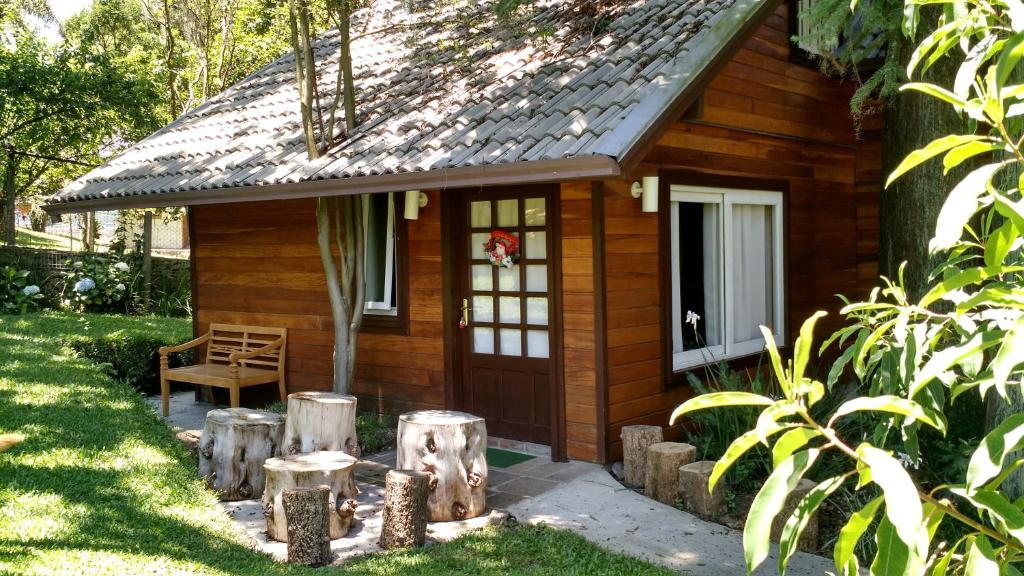 a small wooden cabin with a porch and a chair at Chalé Estilo Alemão - Centro de Canela in Canela