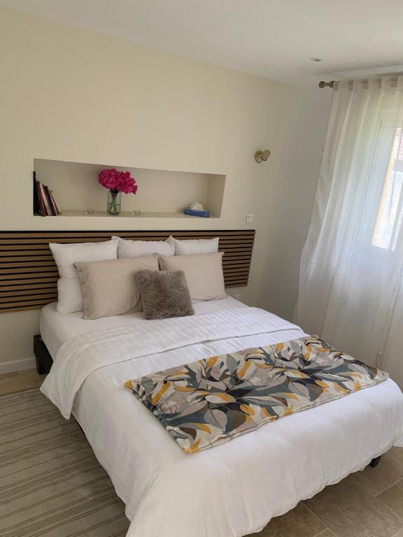 a bedroom with a large white bed with a flower blanket on it at La CléryNette in Les Andelys