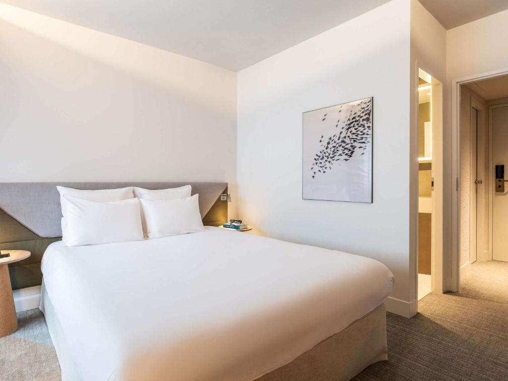 a bedroom with a large white bed in a room at Novotel Brugge Centrum in Bruges