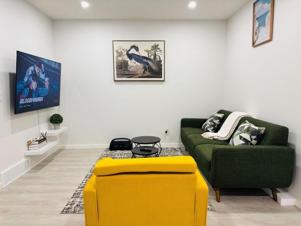 a living room with a green couch and a yellow ottoman at Chic City Escape- come experience tranquility! in Calgary