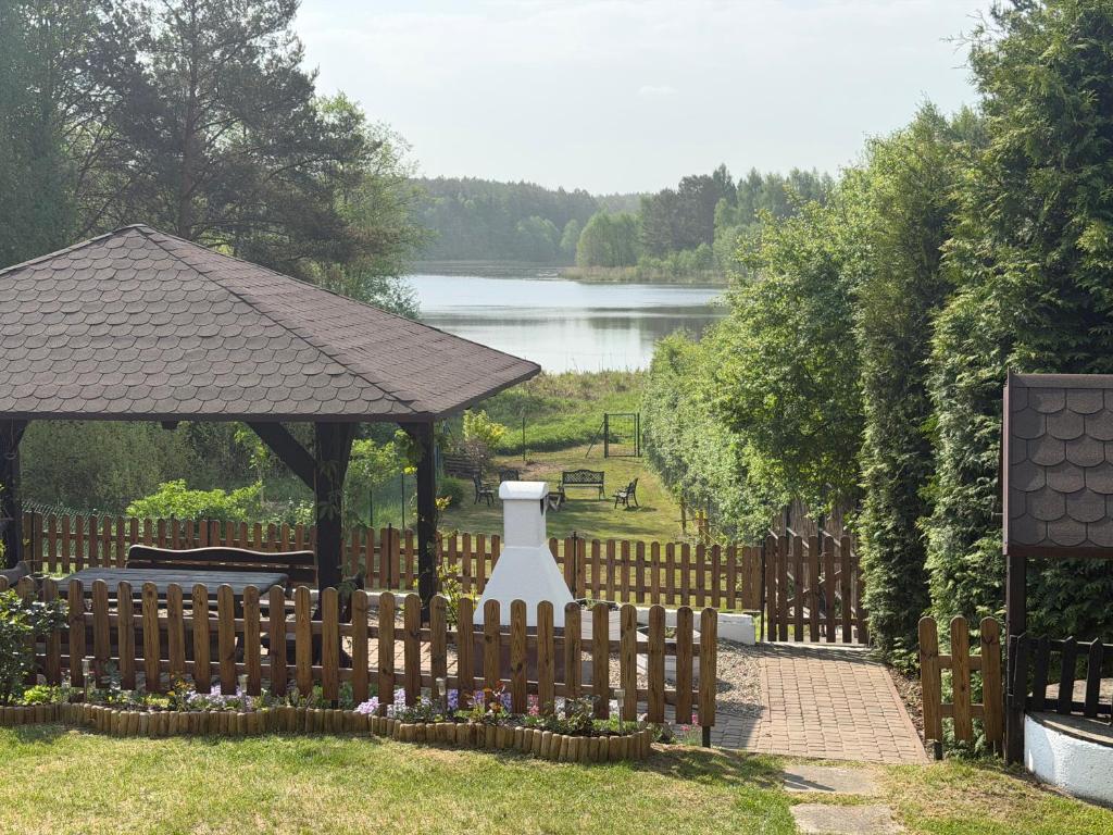 ein Holzzaun mit einem Pavillon neben einem See in der Unterkunft Smolniki Leśna Oaza in Smolniki
