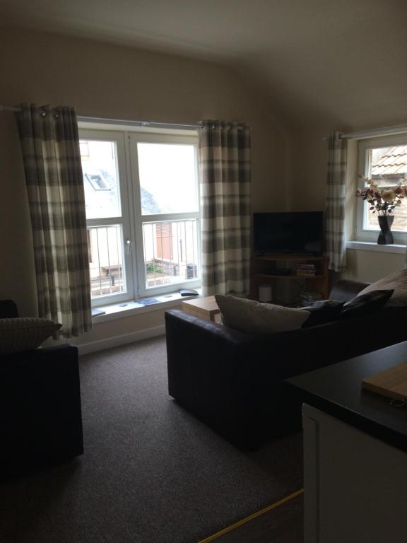 a living room with a couch and two windows at The Old Coach House in Eyemouth