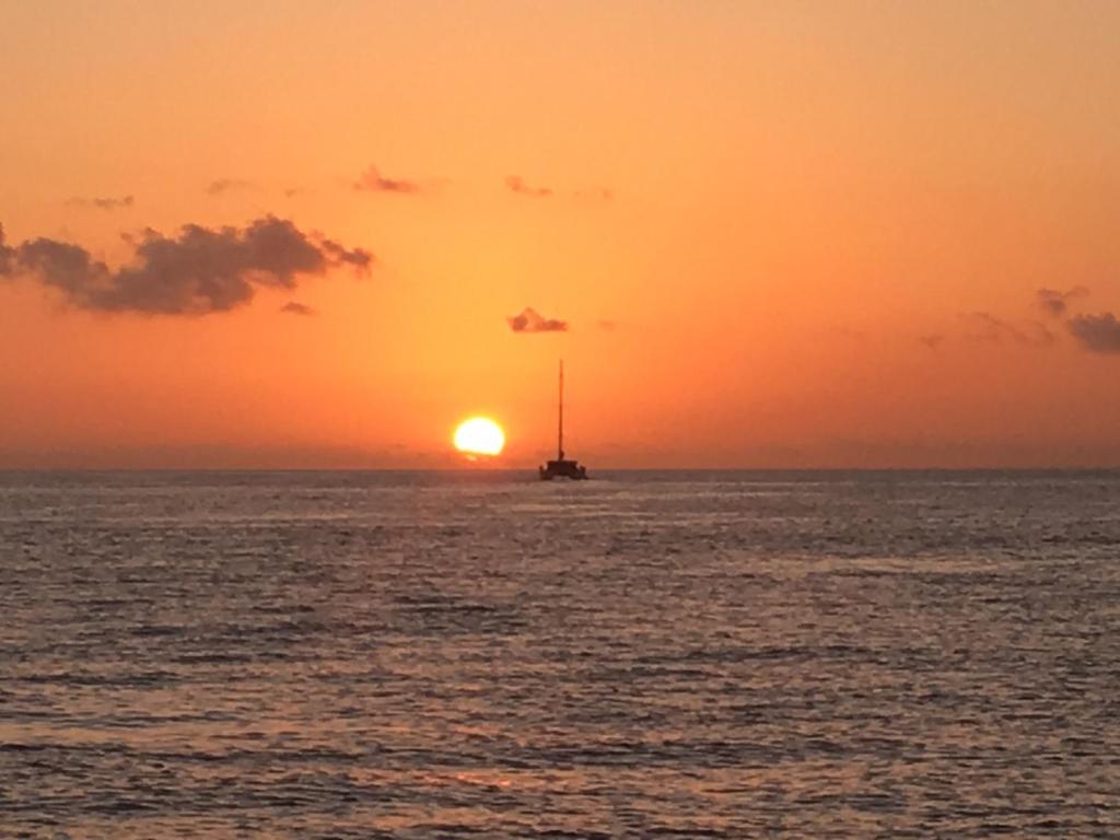 a boat in the ocean with the sunset in the background at Chez Lester in Baie Sainte Anne