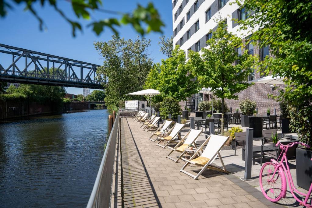 a row of chairs and umbrellas next to a river at INNSiDE by Meliá Hamburg Hafen in Hamburg
