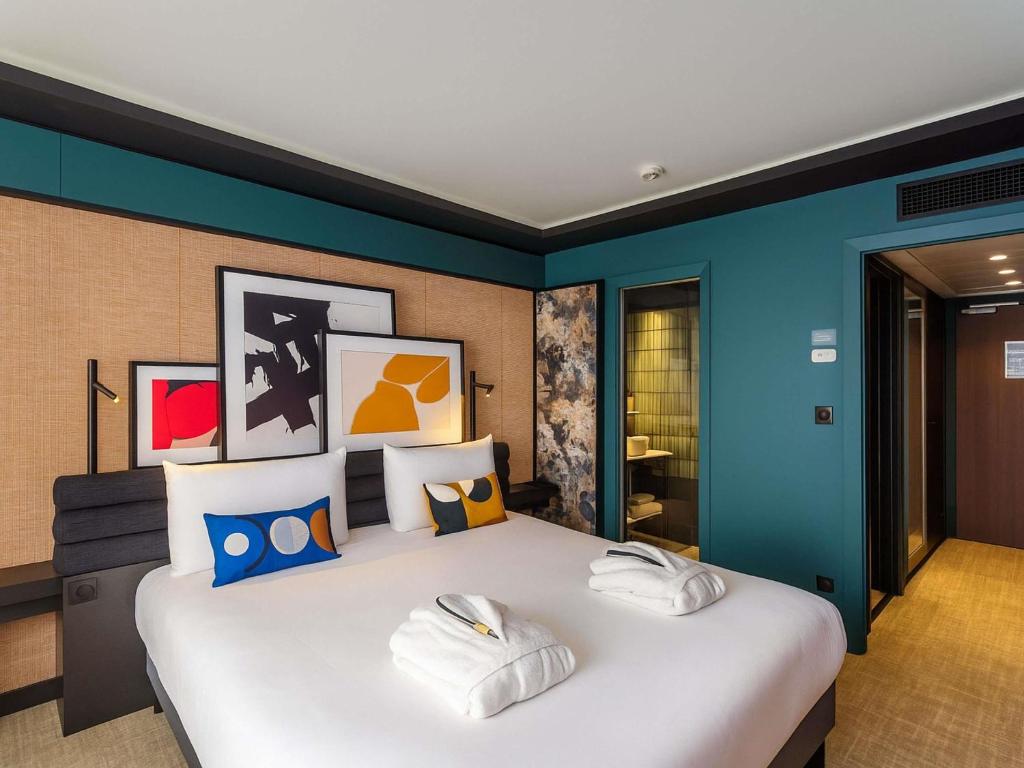 a bedroom with a large white bed with blue walls at Mercure Dijon Centre Clemenceau in Dijon
