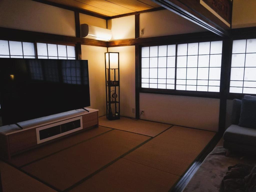 a living room with a flat screen tv and windows at 아라무사aramoosa민숙 in Tsushima