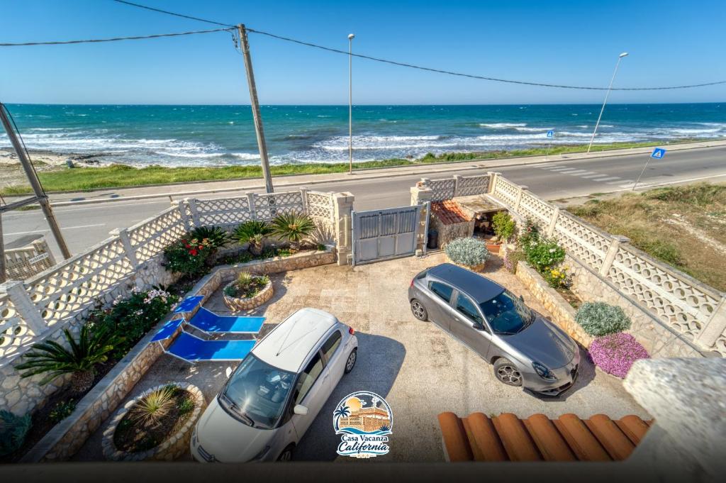 two cars parked in a parking lot near the ocean at Casa Vacanza California in Bari