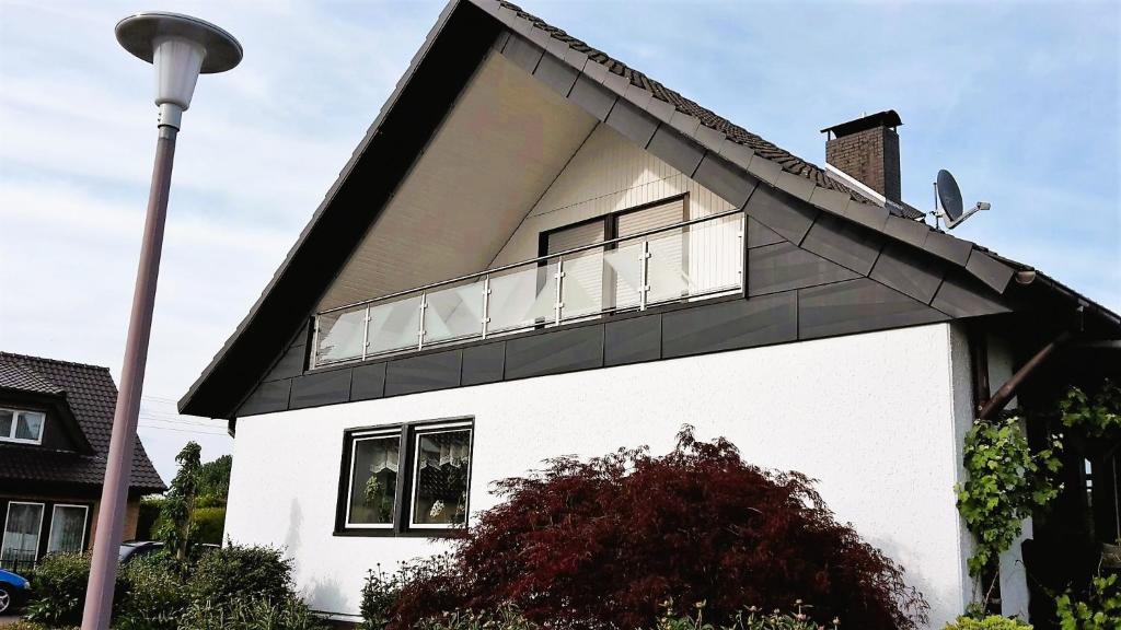 a white house with a black roof and a balcony at Willkommen bei Renate und Jörg in Unna