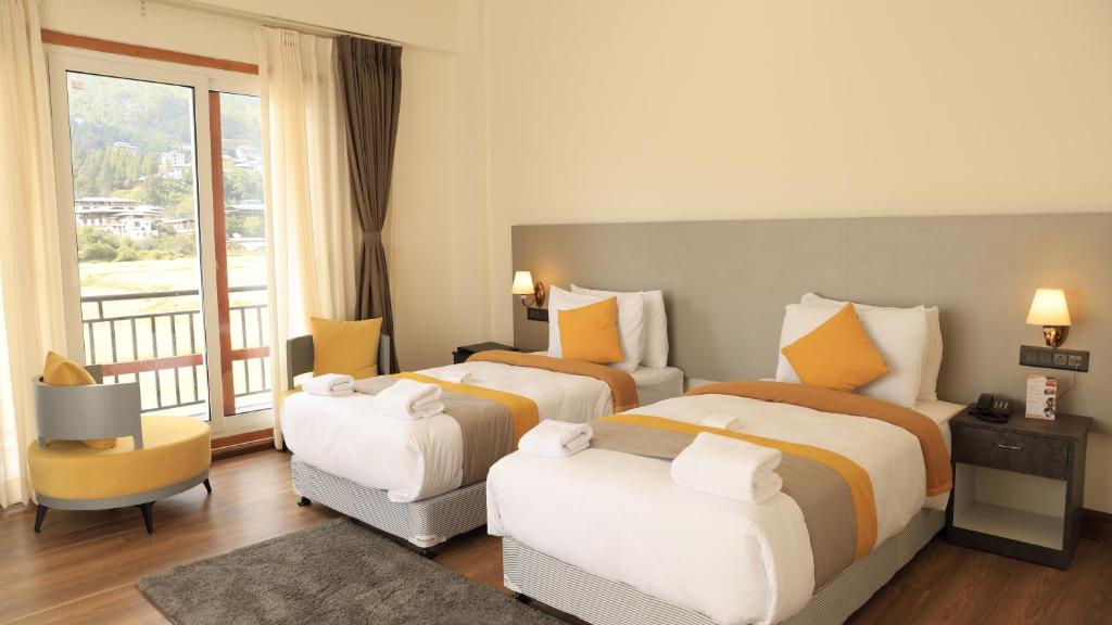 a hotel room with two beds and a balcony at Golden Paddyfield in Paro