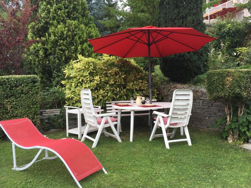 アオスタにあるMaison Bibianの赤い傘付きテーブルと椅子