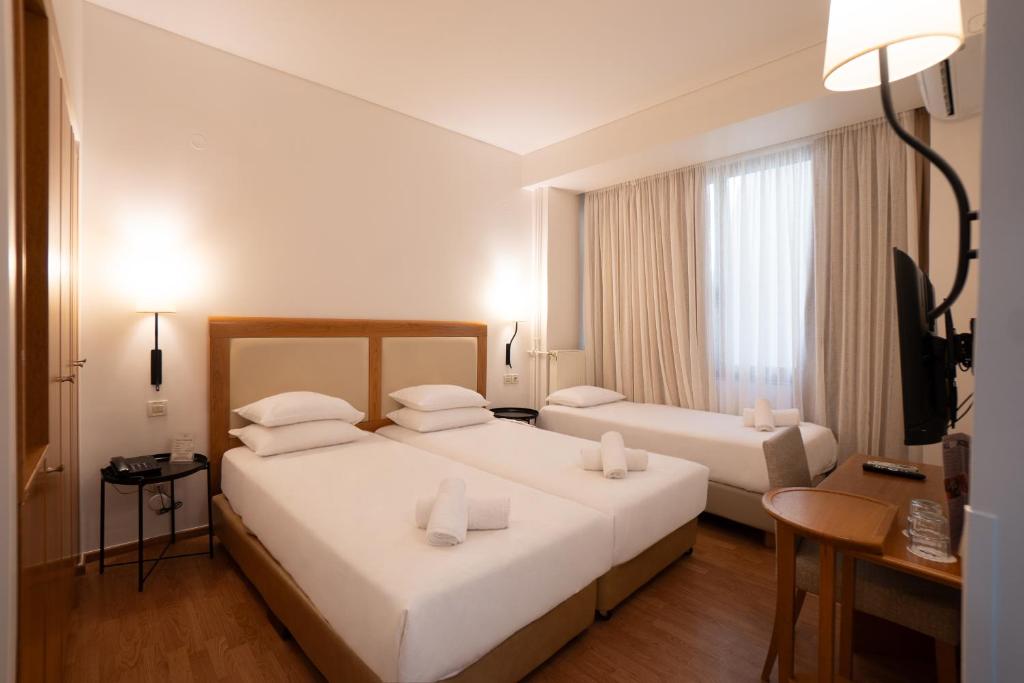 a hotel room with two beds and a window at Olympic Hotel in Heraklio