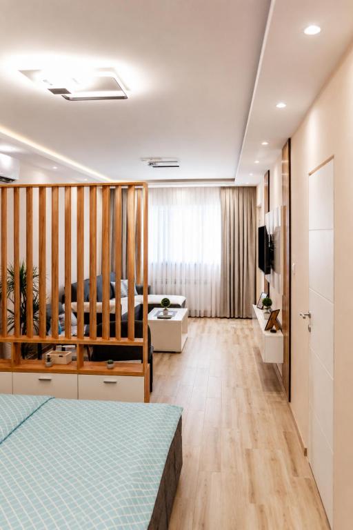 a bedroom with a bed and a living room at Apartman Harmony in Prijedor