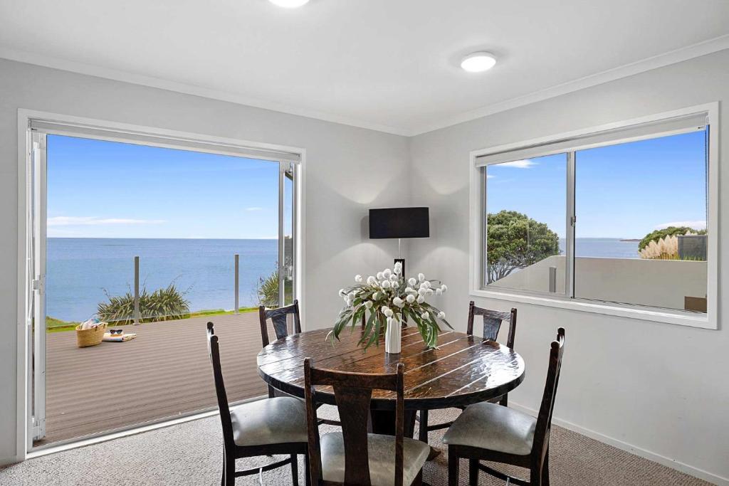 a dining room with a table and a view of the ocean at Beachfront Breeze - sea views for days in New Plymouth
