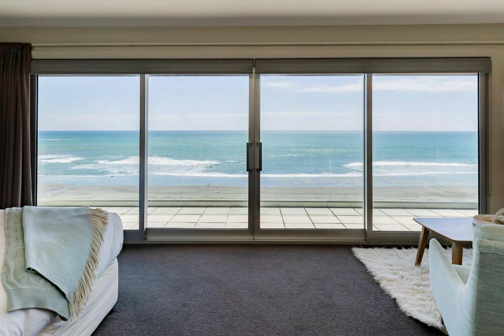 a room with a large window with a view of the ocean at Clifftops - oceanfront retreat in Oakura Beach in Oakura