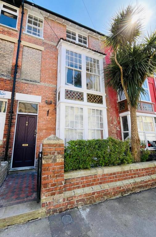a brick house with a palm tree in front of it at Number 29 in Melcombe Regis