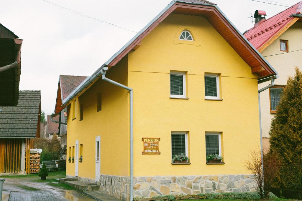 a yellow house with a brown roof at Apartmány Bistár in Zuberec