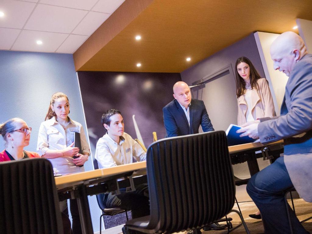 A group meets around tables in a compact, warmly lit conference room.