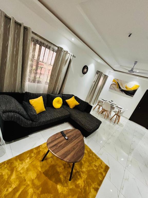 a living room with a black couch and yellow pillows at Casa Leo in Agboogba