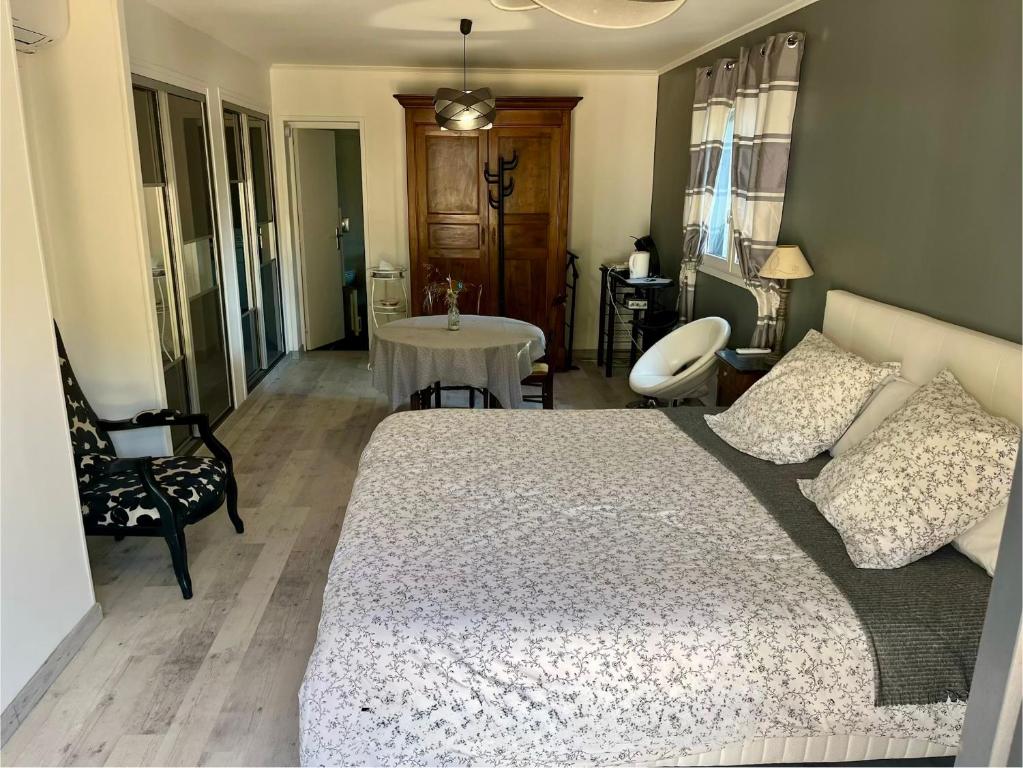a bedroom with a bed and a chair and a table at Grande Chambre meublee in Cornebarrieu