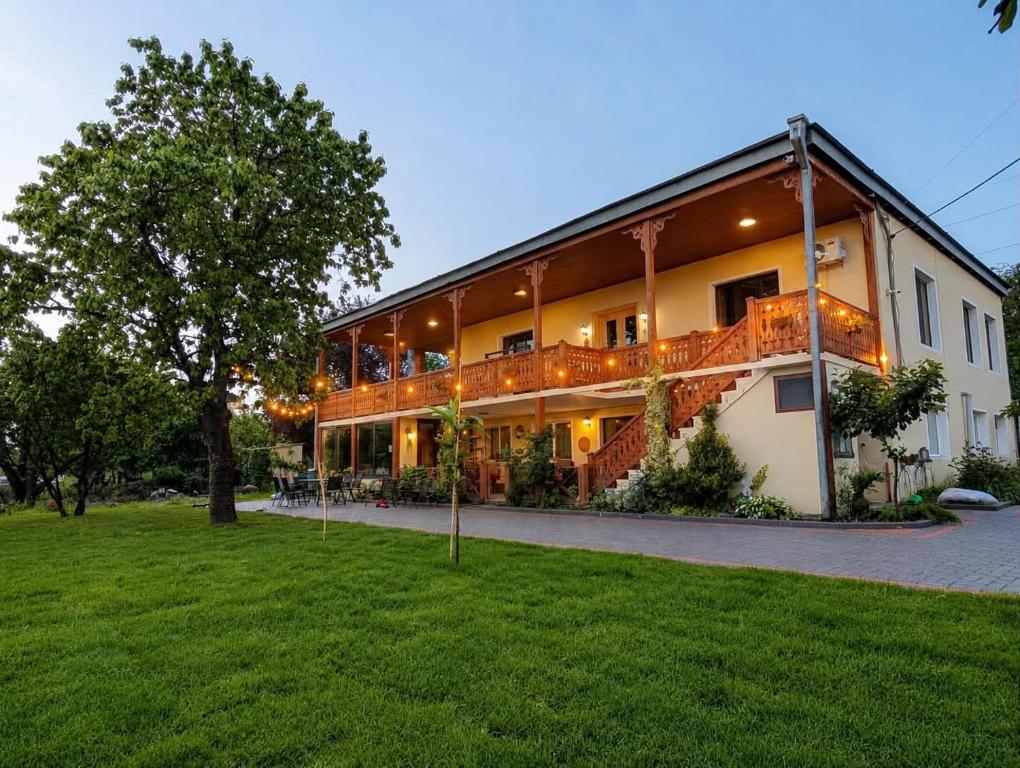 a large house with a large deck on the side of it at Friendly Home in Telavi