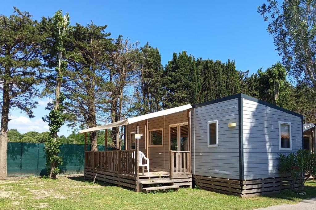 a tiny house with a porch on the grass at mobil-home FONTAINE Jeremie in Canet-en-Roussillon