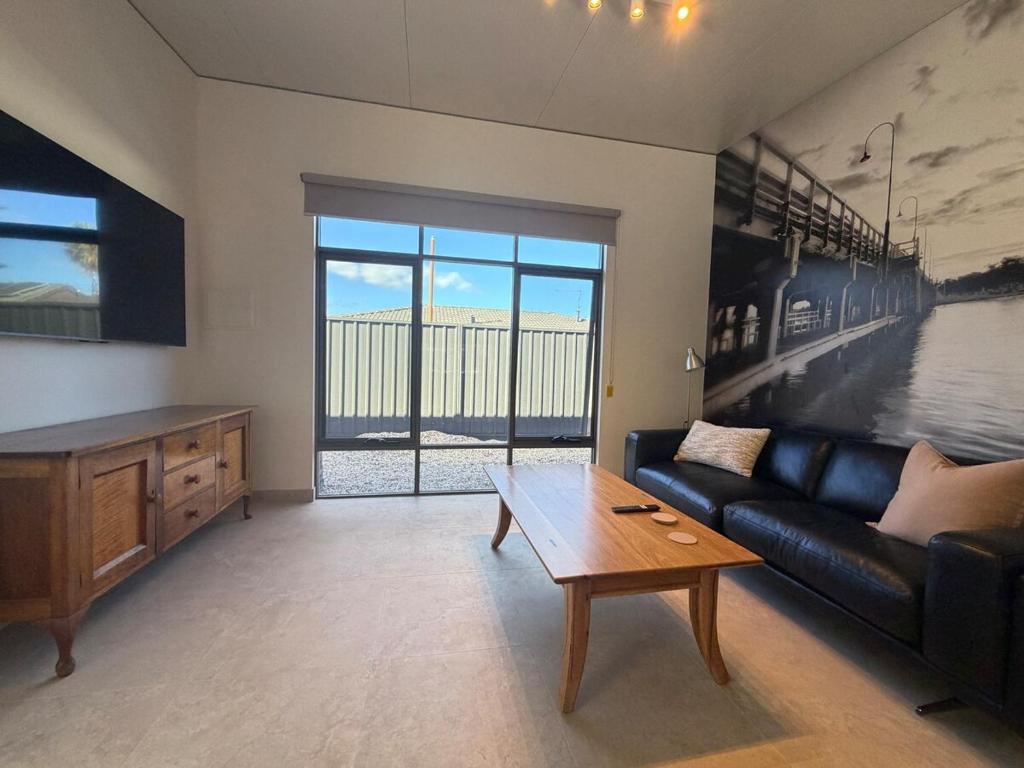 a living room with a black couch and a table at The Mandurah Hideaway in Mandurah