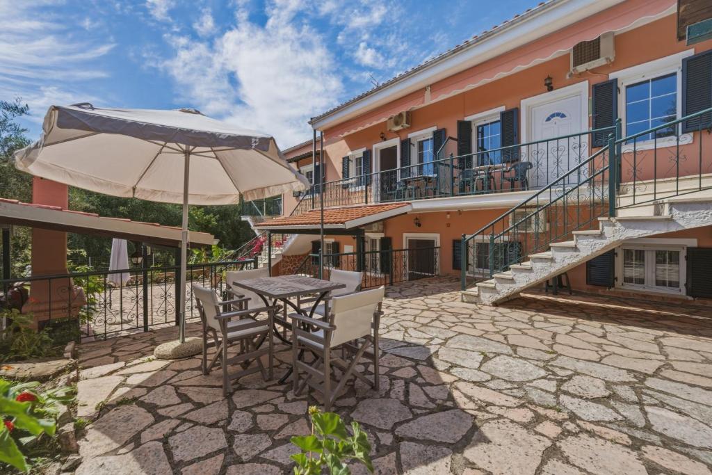 a table and chairs with an umbrella in front of a building at Sivotahomes - Noah in Syvota