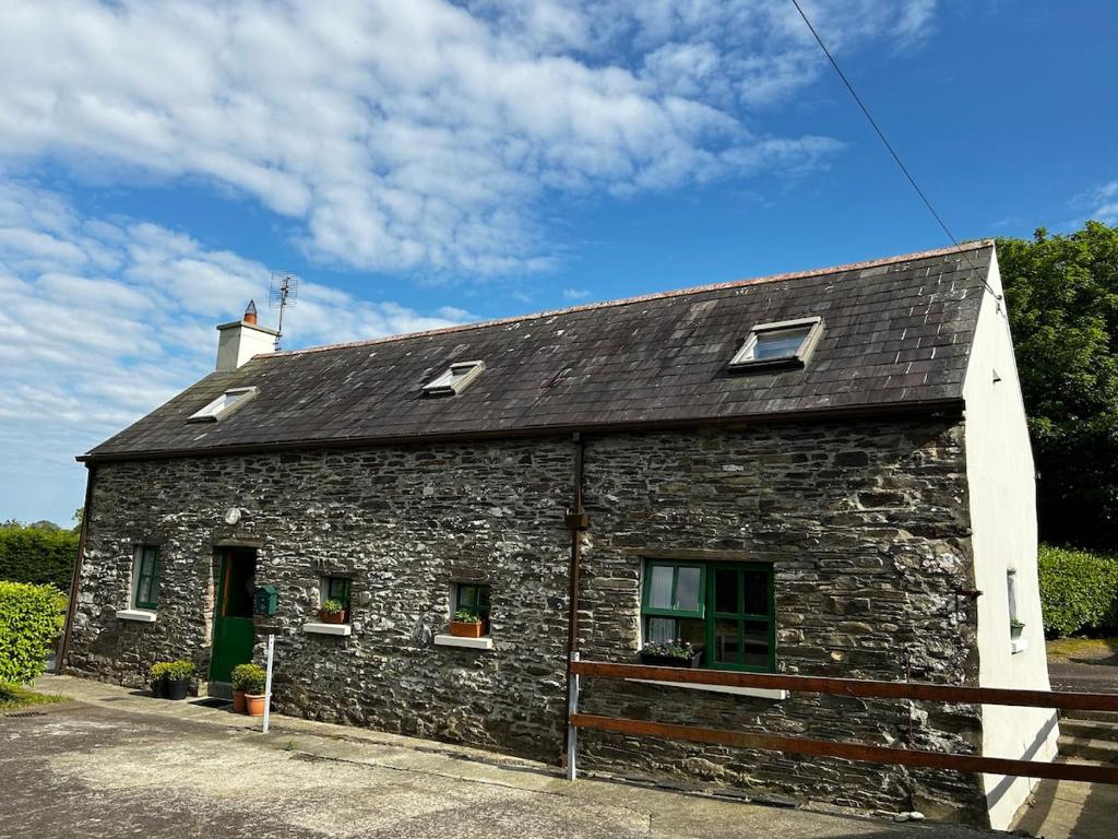 a stone building with windows and a roof at High Field Cottage Rosscarbery in Rosscarbery
