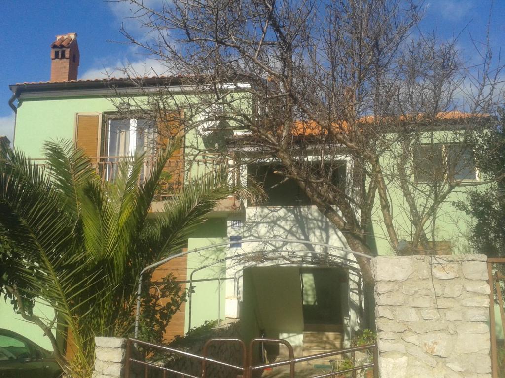 a green and white house with a tree in front of it at Anita studio 3 Apartment in Mali Lošinj