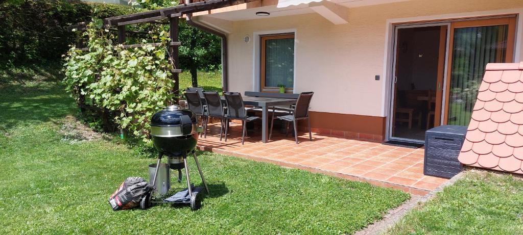a grill sitting in the grass next to a house at Apart House ROJER in Ljubno