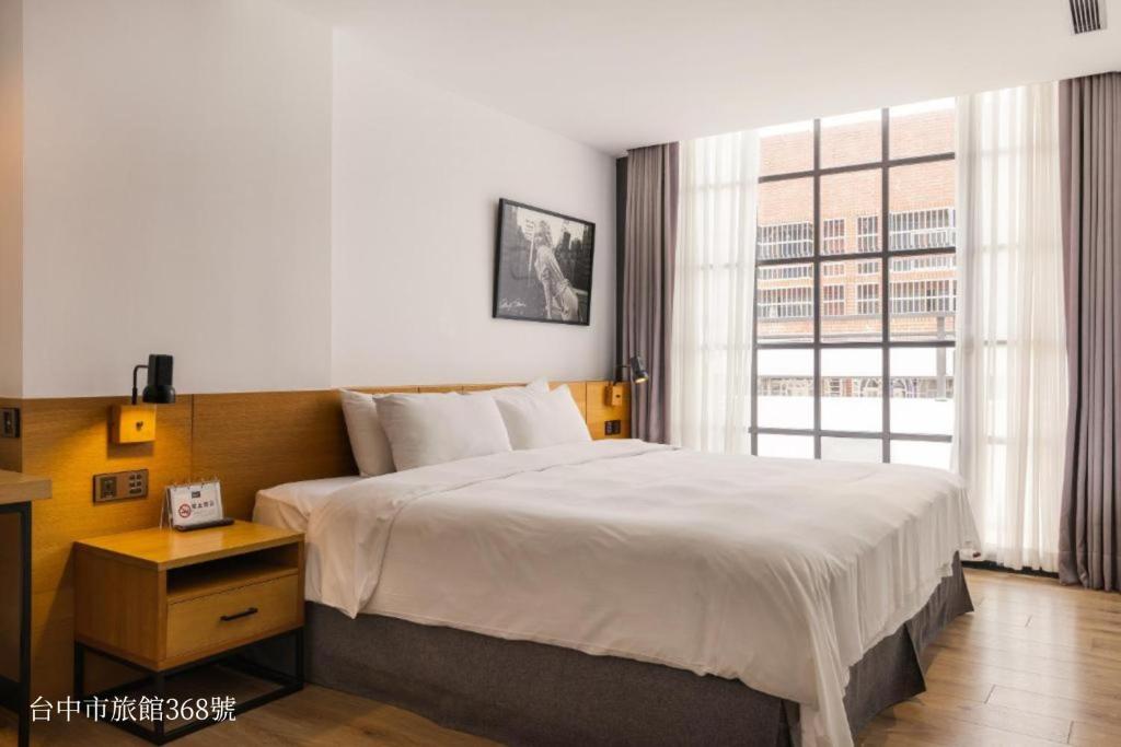a bedroom with a large bed and a large window at BlueSky Hotel in Taichung