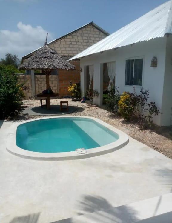 a swimming pool in front of a house with an umbrella at Uroa House in Uroa