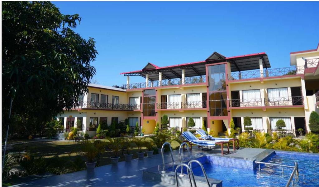 a hotel with a swimming pool in front of it at Blue River Resort in Rāmnagar