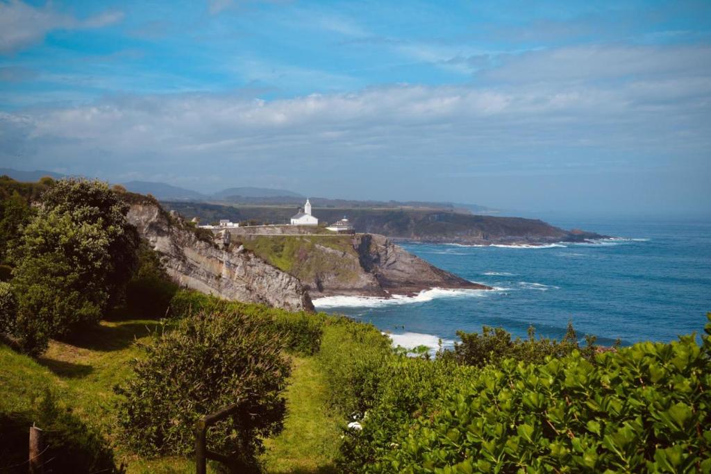 a lighthouse on a cliff next to the ocean at HolaCamp Luarca in Luarca