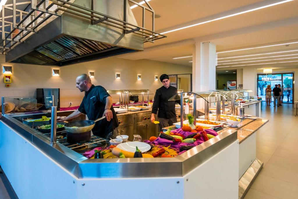two men standing in a kitchen preparing food at Lagomandra Hotel and Spa in Lagomandra