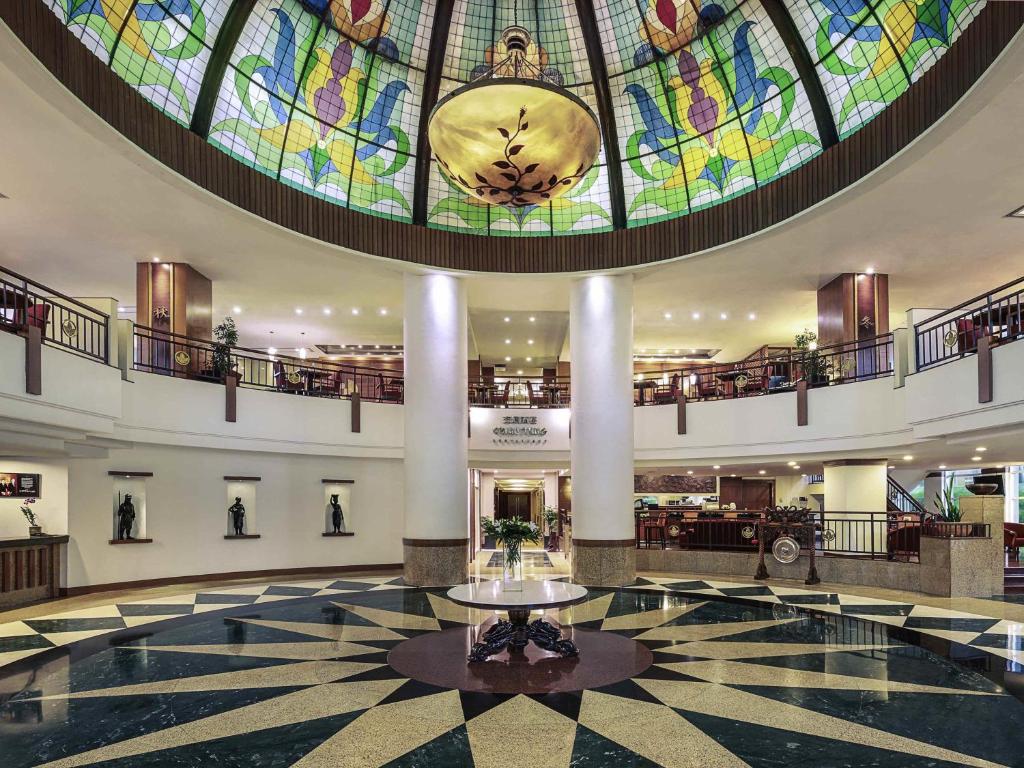 a large lobby with a large stained glass ceiling at Mercure Jakarta Kota in Jakarta