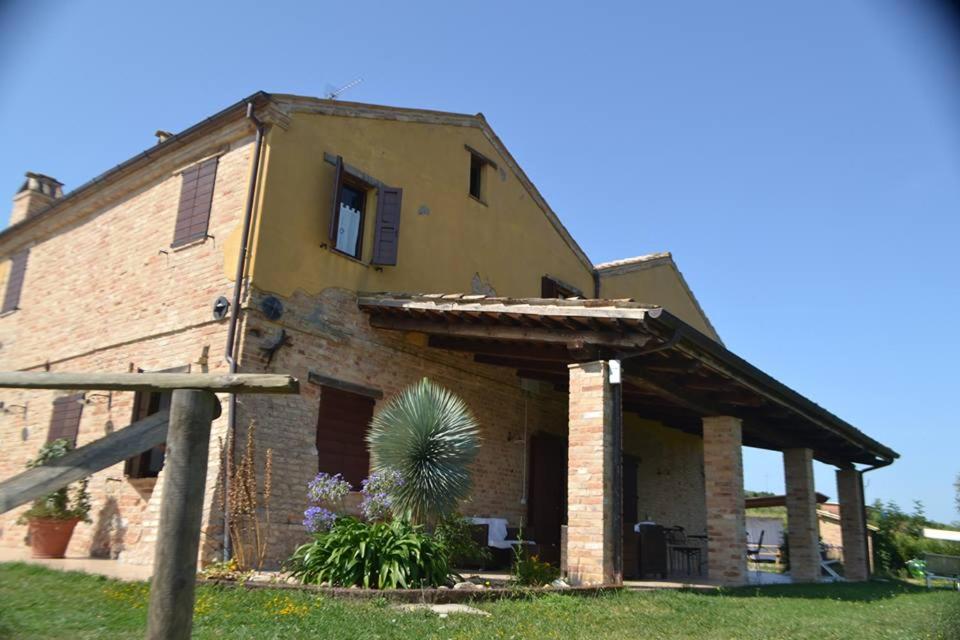 an old brick house with a palm tree in front of it at Agriturismo San Michele in Cossignano
