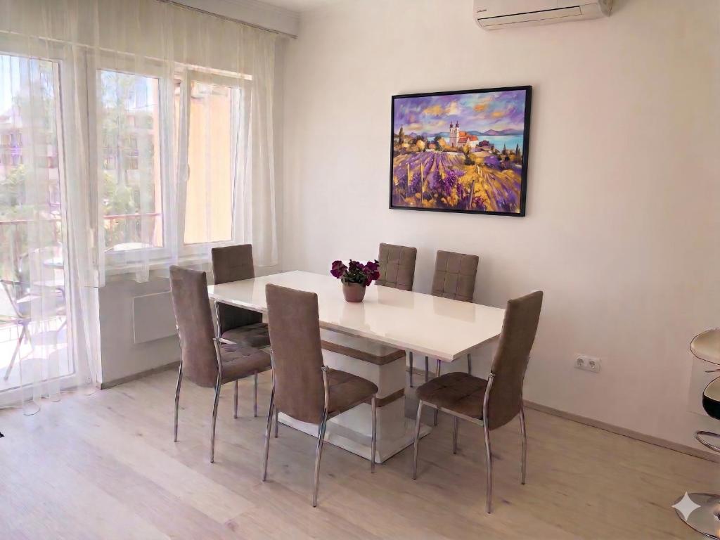 a dining room table with chairs and a painting on the wall at Szende Apartman in Balatonfüred